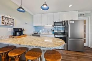 een keuken met een aanrecht met krukken en een koelkast bij Unspoiled Beachfront Villa Sunrises from Balcony in Hilton Head Island