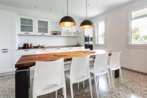 a kitchen with a wooden table and white chairs at CasaTitti Polcenigo in San Giovanni +22 photos