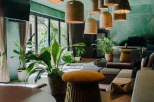 ein Wohnzimmer mit vielen Pflanzen und Pendelleuchten in der Unterkunft Cocoon Sendlinger Tor in München