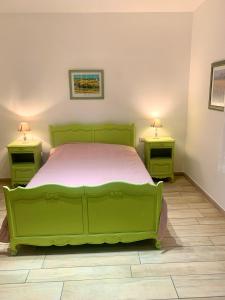 a green bed in a room with two night stands at La Bigotière avec clim et jardin in Arles