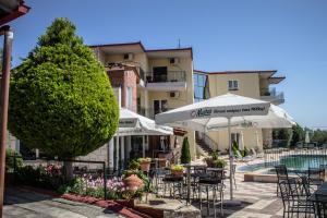 a patio with tables and umbrellas in front of a building at Hotel Ilios in Kriopigi