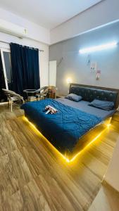 ein Schlafzimmer mit einem Bett mit einer blauen Decke und Beleuchtung in der Unterkunft Serenity suits in Sūrajpur