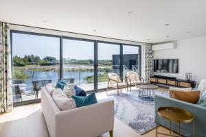 ein Wohnzimmer mit Blick aufs Wasser in der Unterkunft Knighton - Luxury Dorset lakeside home, sleeps 12 with spa and pool access in Warmwell