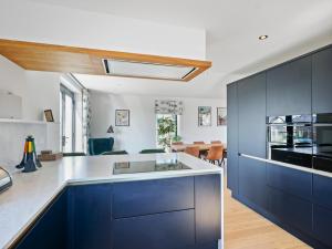 eine Küche mit blauen Schränken und einem Esszimmer in der Unterkunft Knighton - Luxury Dorset lakeside home, sleeps 12 with spa and pool access in Warmwell