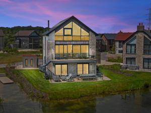 ein großes Haus mit einem Fluss davor in der Unterkunft Knighton - Luxury Dorset lakeside home, sleeps 12 with spa and pool access in Warmwell