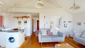 a kitchen and living room with a couch and a washing machine at D22 Sandelite, Riviere Towans in Hayle