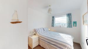 a white bedroom with a bed and a window at D22 Sandelite, Riviere Towans in Hayle