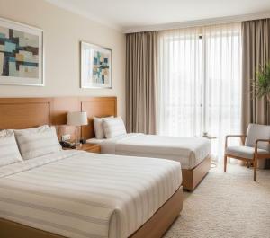 una stanza d'albergo con due letti e una sedia di Zafer Hotel a Malatya Altre 16 foto