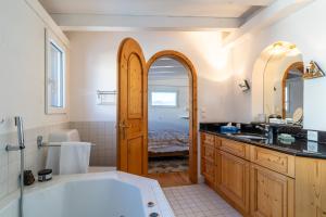 een badkamer met een groot wit bad en een wastafel bij Edelweiss Schlosswohnung in Flims