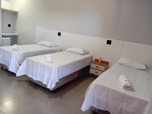 zwei Betten in einem Zimmer mit weißen Wänden in der Unterkunft Hotel Tamboril in Barra Bonita