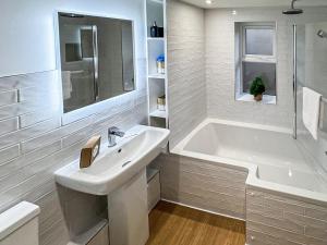 een witte badkamer met een wastafel en een bad bij Cygnet Cottage in Warkworth