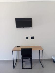 un tavolo in legno con sedia e una televisione su una parete di Hotel Tamboril a Barra Bonita