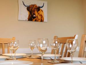een tafel met wijnglazen en een koe aan de muur bij Ninetrees - Uk47883 in Keilour