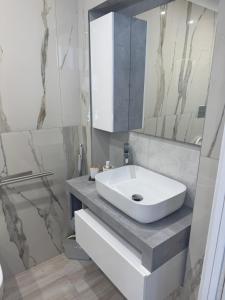 un bagno bianco con lavandino e specchio di South Blue Apartment a Trani