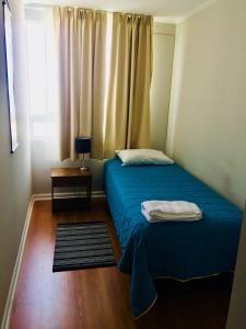 een kleine slaapkamer met een blauw bed en een raam bij Arriendo Iquique frente a Playa Brava in Iquique