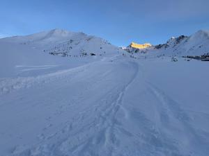 a snow covered hill with a mountain in the background at Top Residence Trilocale Larice in Passo del Tonale +1 photo