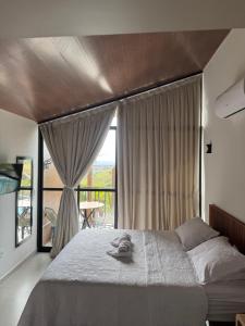 a bedroom with a large bed and a balcony at CHALE VILAALICE in Monte das Gameleiras