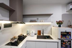 胡志明市Hera House l Vinhomes Grand Park的白色的厨房配有炉灶和水槽