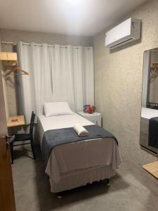 a small bedroom with a bed and a mirror at Pousada Arena 165 in Murici