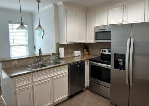 a kitchen with white cabinets and a stainless steel refrigerator at The Beach Peach in Port Aransas
