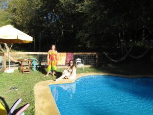 Dos mujeres están sentadas junto a una piscina. en HOTEL & HOSTAL CHIL'IN, Las Trancas, en Las Trancas