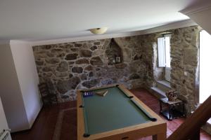 a pool table in a room with a stone wall at Qt Refúgio de Rubiães Villa 1-2 Paredes de Coura in Paredes de Coura