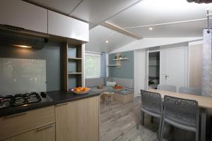 een keuken met een aanrecht en een tafel met stoelen bij Camping 4 étoiles - Piscine - eeihec in Loupiac