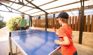 een jonge jongen die voor een tafeltennisbaan staat bij Camping 4 étoiles - Piscine - eeihec in Loupiac