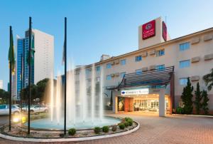 a hotel with a fountain in front of a building at Comfort Suites Flamboyant Goiânia in Goiânia