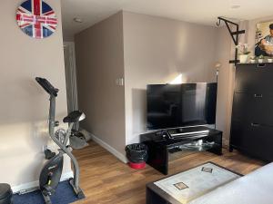 een woonkamer met een loopband en een flatscreen-tv bij One Bedroom Flat in London Heathrow 20 minutes drive in Greenford