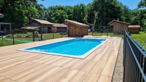 een zwembad met een houten terras en een hek bij La cheneraie in Mano