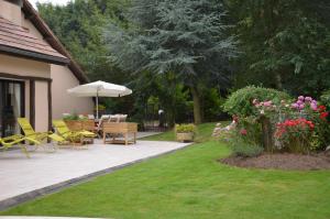 a patio with chairs and an umbrella in a garden at La Villa Antalya in Ault