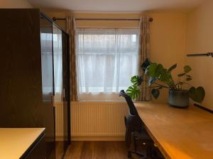 ein Büro mit einem Schreibtisch und einem Fenster mit einer Pflanze in der Unterkunft One Bedroom Flat in London Heathrow 20 minutes drive in Greenford