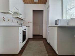 a kitchen with white cabinets and a microwave at Spacious Apartment for 5 in Sodankylä