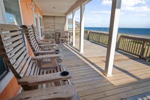 a porch with wooden benches on a house with the ocean at Beachfront Home with Huge Deck in Bolivar Peninsula