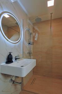 un bagno con un lavandino bianco e uno specchio di HELIOS - Seaside Pool Villa & Private Parking a Olympiakí Aktí