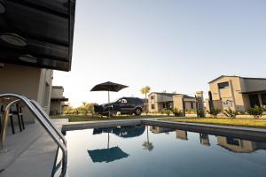 una piscina con auto parcheggiata accanto a un edificio di HELIOS - Seaside Pool Villa & Private Parking a Olympiakí Aktí