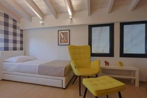una camera da letto con un letto e una sedia gialla di HELIOS - Seaside Pool Villa & Private Parking a Olympiakí Aktí Altre 24 foto