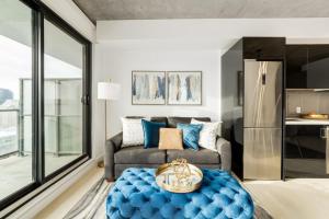 a living room with a couch and a blue ottoman at Spacious and Stylish Modern Condo in Calgary in Calgary