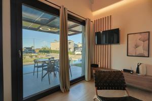un soggiorno con porta scorrevole in vetro e tavolo da pranzo di HELIOS - Seaside Pool Villa & Private Parking a Olympiakí Aktí