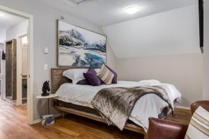 a bedroom with a large bed with purple pillows at Cozy getaway for exploring Canmore and Banff in Canmore