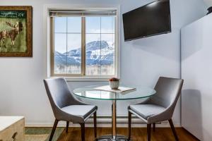 a table and two chairs in a room with a window at Cozy Mountain View Condo Close to DT Canmore in Canmore