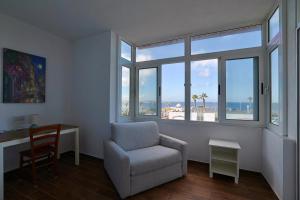 een woonkamer met een stoel, een bureau en ramen bij SeaView Escape with Pool Access in St Paul's Bay