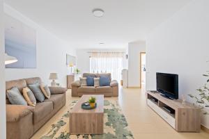a living room with a couch and a tv at Cabanas Beach T2 in Cabanas de Tavira