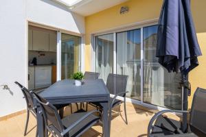 a dining room table with chairs and an umbrella at Cabanas Beach T2 in Cabanas de Tavira