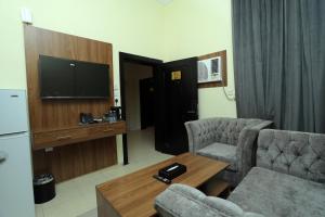 un soggiorno con un divano, un tavolo e una TV di منازل الحساء للشقق الفندقية a Al Hofuf