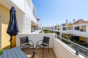 a balcony with a table and chairs and an umbrella at Cabanas Beach T2 in Cabanas de Tavira