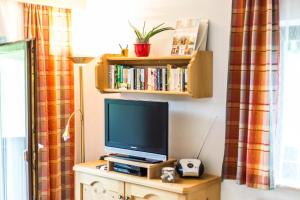 a tv sitting on top of a dresser with a book shelf at Appartement SONNENGLÜCK by MoniCare in Leutasch