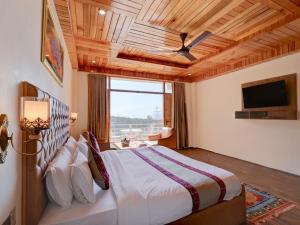 a bedroom with a large bed with a ceiling fan at Omavya luxury hotel & cottage -with bonfire , apple orchid ,mountain view , parking in Vashisht
