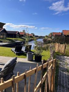 a backyard with a wooden fence and a river at Lauwershuisje, Sauna, Harbour Lauwersmeer in Anjum